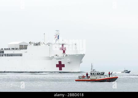 NEW YORK, NY - 30. MÄRZ: Das Militär-Sealift-Kommando-Lazarettschiff USNS Comfort (T-AH 20) wird von der US-Küstenwache, der New Yorker Polizeibehörde und den Anlagen der New Yorker Feuerwehr begleitet, wenn das Schiff in New York City, 30. März 2020 ankommt. Komfort, der zur Unterstützung der COVID-19-Reaktionsbemühungen des Landes eingesetzt wird und als Überweisungskrankenhaus für nicht-COVID-19-Patienten dient, die derzeit in Landkrankenhäusern eingeliefert werden. So können Krankenhäuser in Landhäusern ihre Bemühungen auf COVID-19-Fälle konzentrieren. Eine der Missionen des Verteidigungsministeriums ist die Verteidigungsunterstützung von Zivilbehörden. DoD wird unterstützt Stockfoto