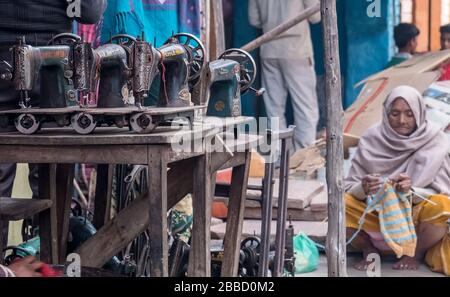Alte indische Frau sitzt vor einer Nähmaschinenwerkstatt Stricken Stockfoto