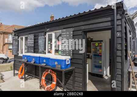 The Fish Shack, eine schwarze Klapperbretthütte, die frisch gefangenen Fisch verkauft, am Strand am Badeort Aldeburgh, Suffolk, Großbritannien Stockfoto