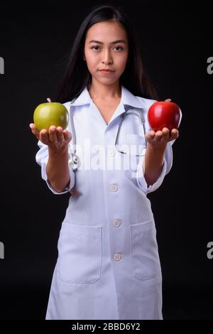 Junge asiatische Frau Doktor als Ernährungswissenschaftlerin, die zwei Äpfel hält Stockfoto