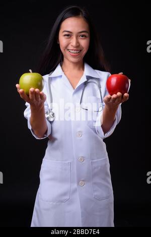 Fröhliche junge Asiatische Frau Doktor als Ernährungsberaterin, die zwei Äpfel hält Stockfoto