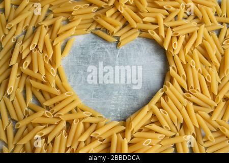 Lebensmittelhintergrund - trockene Penne Pasta mit Herzform für Text, Vollweizen ohne Zutat Stockfoto