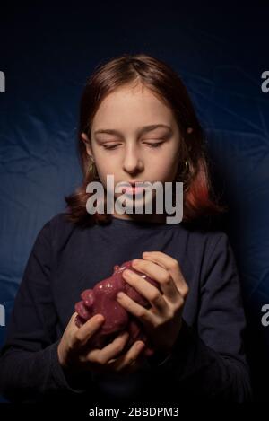 Mädchen mit einem Schleim. Kleines Mädchen, das hausgemachtes Spielzeug macht. Kind hat Spaß, lila Slime zu machen. Kind spielt mit Slime. Entspannung und Zufriedenheit. Ungewöhnlich zufrieden Stockfoto