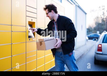 Ein Mann bringt Pakete an eine Verpackungsstation oder holt sie ab Stockfoto