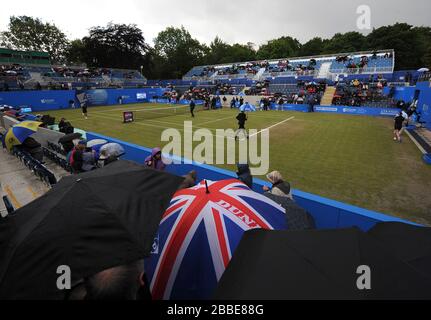 Die Zuschauer nehmen mit Sonnenschirmen Deckung, während sich das Bodenpersonal darauf vorbereitet, die Abdeckungen auf dem Mittelplatz vor jedem Spiel im Halbfinale zwischen Magdelana Rybarikova und Donna Vekic anzubringen. Stockfoto