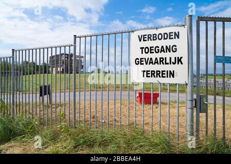 Kein Umbruch, gefährlicher Bereich (verboden toegang, gevaarlijk terrein in niederländischer Sprache) an einem Metallzaun vor einer Ruine einer alten Fabrik Stockfoto