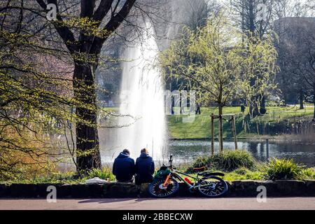 27.03.2020, Essen, Ruhrgebiet, Nordrhein-Westfalen, Deutschland - Freizeit im Stadtpark zur Zeit der Coronakrise sitzt ein junges Paar Stockfoto