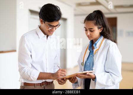 Zwei junge Ärzte diskutieren im Flur in einem Krankenhaus über etwas Stockfoto