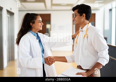 Zwei junge Ärzte diskutieren im Flur in einem Krankenhaus über etwas Stockfoto