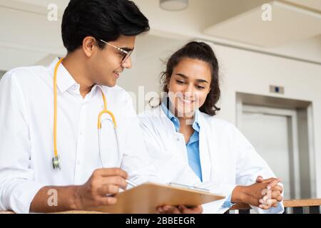 Zwei junge Ärzte diskutieren im Flur in einem Krankenhaus über etwas Stockfoto