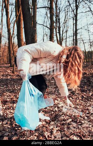 Junge Frau säubert einen Wald. Freiwillige Entnahme von Plastikmüll in Taschen. Konzept der Kunststoffverschmutzung und zu viele Kunststoffabfälle. Umweltbelange Stockfoto