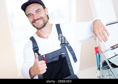 Attraktiver, freundlich lächelnder Handwerker in Arbeitskleidung und mit Werkzeug Stockfoto