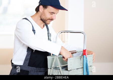 Attraktiver, freundlich lächelnder Handwerker in Arbeitskleidung und mit Werkzeug Stockfoto