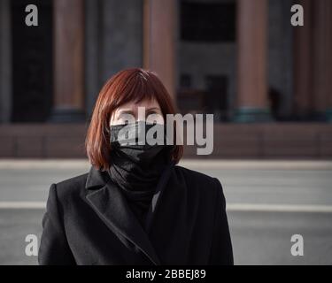 Eine traurige Frau mit Maske auf dem Gesicht steht in der Nähe des geschlossenen Museums. Verbot von Spaziergängen und Besuchen öffentlicher Orte aufgrund einer Coronavirus-Pandemie Stockfoto
