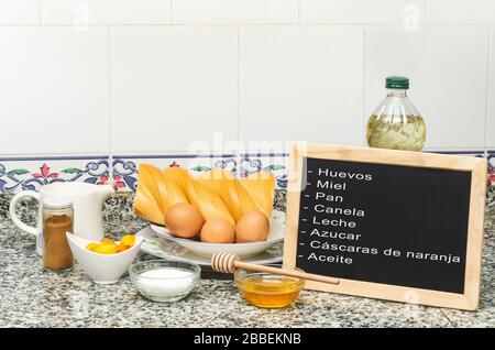 Stillleben mit den Zutaten zum Anstoßen auf französisch. Tafel sagt Eier, Honig, Brot, Zimt, Milch, Zucker, Orangenschälchen, Öl Stockfoto