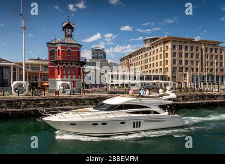 Südafrika, Westkaper, Kapstadt, Victoria und Alfred Waterfront, teures Motorboot, das an der Drehbrücke am historischen Uhrturm vorbeiführt Stockfoto