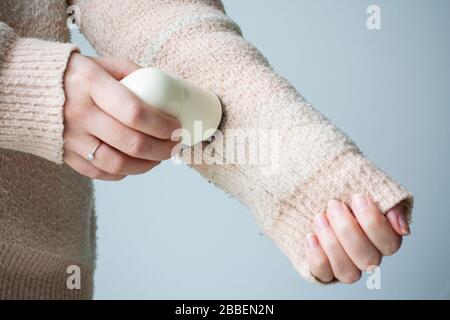 Pullover mit Pillerfüllung. Frau, die einen alten Pullover mit Flusen (Pilling) trägt. Frau verwendet einen tragbaren Rasierer mit Fuzz-Entferner-Gerät Stockfoto