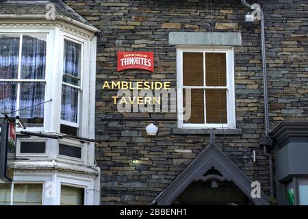 Ambleside, Cumbria, Großbritannien - 16. Mai 2019: Beschilderung an der Trockensteinwand, die auf Thwaites Brauerei und Ambleside Tavern hinweist Stockfoto