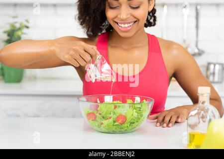 Schöne junge schwarze Frau, die Gemüsesalat zubereitet Stockfoto