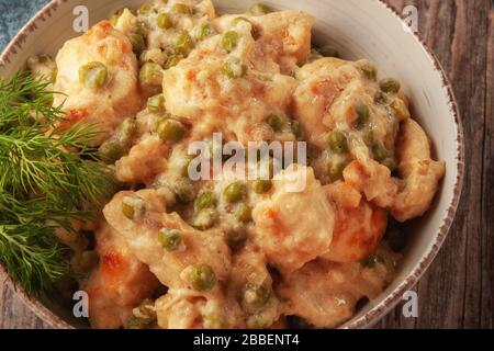 Geschmortes Hühnerfilet mit grünen Erbsen auf einem Holztisch Stockfoto