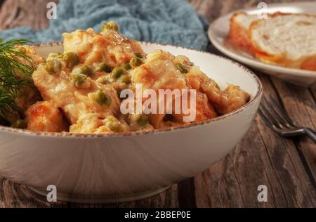 Geschmortes Hühnerfilet mit grünen Erbsen auf einem Holztisch Stockfoto