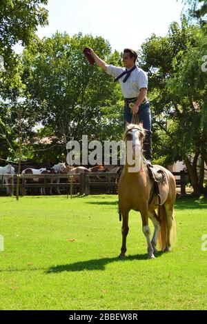 Estancia El Ombu de Areco, Argentinien - Februar 2019: (Jung) Gaucho zeigt sein Leben und seine Arbeit auf einer typischen argentinischen Farm, die mit seinem Lieblingspferd reitet Stockfoto