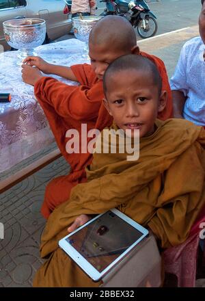 Kampot, Kambodscha, Asien: Kinderstudent einer buddhistischen Schule spielt mit seiner Tablette Stockfoto