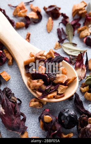 Kräuterfruchtetee mit Holzlöffel auf blauem Grund. Eisbeere mit Lingonbeerblatt, apfel und Hibiskus. Draufsicht flach lag dicht oben Stockfoto