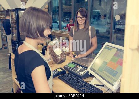 Female Shop Assistant ein Kunde an einem Schreibtisch. Stockfoto
