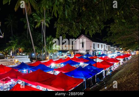 Nachtmarkt in Luang Prabang, Laos. Berühmt für lokale Souvenir- und Handwerke. Licht scheint durch Zelte und blickt auf das Gebäude im Kolonialstil. Stockfoto