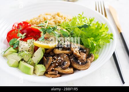 Modischer Salat. Vegane Buddhaschüssel mit Linsen, Avocado, Pilzen, Salat, Tomaten und chia. Internationaler Tag Ohne Fleisch. Vegetarischer Salat. Stockfoto
