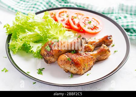 Gegrillte Hühnerbeine mit Gewürzen und frischem Gemüse. Gebackene Trommeln. Stockfoto