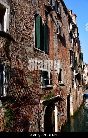 Venedig, Italy-Februar 2020; Nahaufnahme eines Abschnitts eines historischen Gebäudes in Venedig mit extrem verwitterter Fassade entlang einer schmalen cana Stockfoto