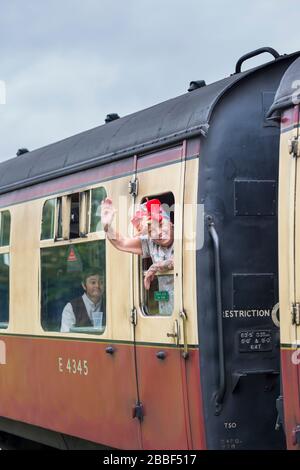 Lächelnde britische Passagierin der 1940er Jahre, die aus dem alten Eisenbahnwagen ausbeugte und von der Dampfeisenbahn Abschied winkte, Kriegsereignis der Severn Valley Heritage Railway aus dem 2. Weltkrieg. Stockfoto