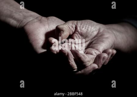 Nahaufnahme eines jungen kaukasischen Mannes, der die Hand einer älteren kaukasischen Frau hält Stockfoto