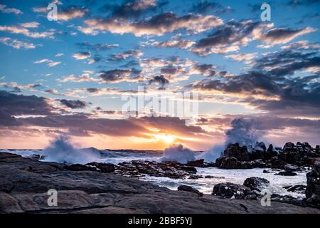 Südafrika, Cape St Francis, Sun Going Down, über den Indischen Ozean und die Wellen schlagen auf den Rocks. Stockfoto