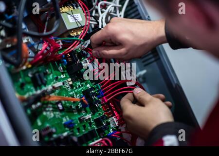 Nahaufnahme des Elektrotechnikers, der mit elektrischen Kabeldrähten des modernen Sicherungsschalterkastens arbeitet. Elektrische Geräte zur Einstellung der neuen Spannungsverkabelung Stockfoto