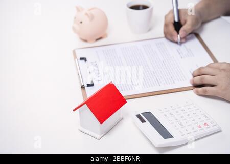 Geschäftskonzept - Der Junge Asiat in blauem Hemd berechnet, unterzeichnet den Vertrag über den Kauf einer Hauskreditzahlung, die Zahlung von Versicherungen, Steuern, Nahaufnahme. Stockfoto