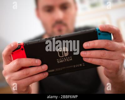 Großbritannien, März 2020: Nintendo Switch Erwachsener Spieler auf Handspielkonsole mit Logo Stockfoto