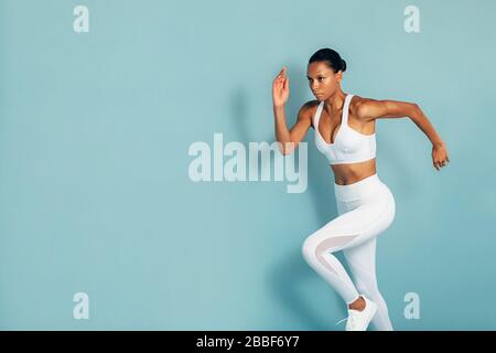 3/4-Schuss Fitnessfrau in weißer Sportswear über blauem Hintergrund Stockfoto