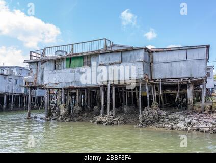 Altes zerfallendes Haus auf Stelzen über Wasser in Hongkong. Stockfoto