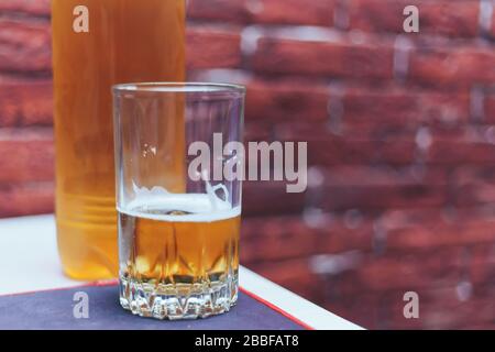 Bier in Glas und Plastikflasche auf dem Tisch, Mann zuhause Stockfoto