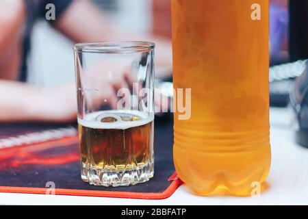 Bier in Glas und Plastikflasche auf dem Tisch, Mann zuhause Stockfoto