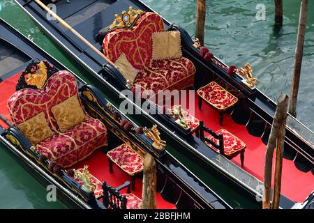 Hoher Winkel, Nahaufnahme des schönen roten Innenraums einer traditionellen, an Stangen gefesterten Gondel in Venedig Stockfoto