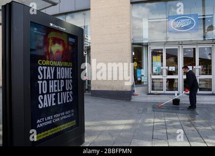 Birmingham, West Midlands, Großbritannien. März 2020. Ein Arbeiter reinigt die Schritte eines Boots Chemikers vor einer NHS-Anzeige in der Innenstadt von Birmingham während der Pandemieabsperrung von Coronavirus. Credit Darren Staples/Alamy Live News. Stockfoto