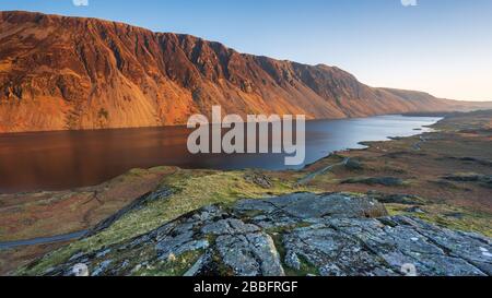 Illgill Head, auch bekannt als The Screes, leuchtet im letzten Licht eines Frühlingstages rot über den dunkelblauen Tiefen von Wast Water, Lake District, Großbritannien. Stockfoto