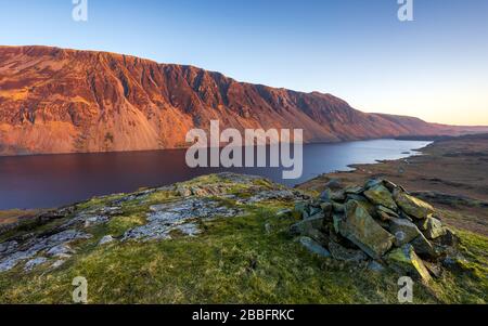 Illgill Head, auch bekannt als The Screes, leuchtet im letzten Licht eines Frühlingstages rot über den dunkelblauen Tiefen von Wast Water, Lake District, Großbritannien. Stockfoto