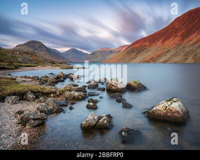 Illgill Head, auch bekannt als The Screes, leuchtet im letzten Licht eines Frühlingstages rot über den dunkelblauen Tiefen von Wast Water, Lake District, Großbritannien. Stockfoto