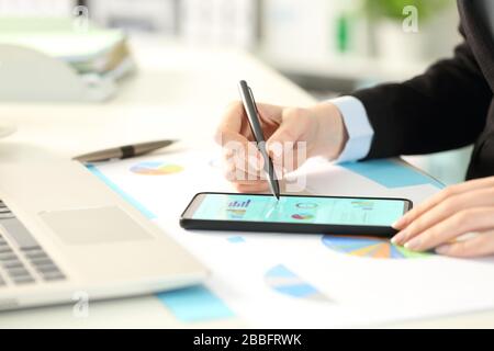 Nahaufnahme der Geschäftsfrau übergibt das Überprüfen von Diagrammen auf dem Smartphone im Büro Stockfoto