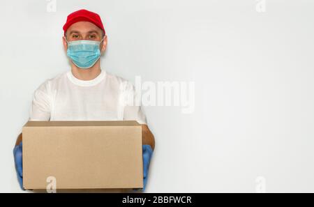 Mitarbeiter, der die Kartonverpackung in medizinischen Handschuhen und Maske ausliefert.?Onkept der Zustellung von Sicherheitspost per Kurier in Quarantäne von Viren oder Coronavirus Stockfoto